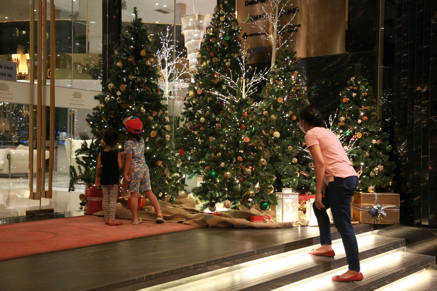 Hai em nhỏ thích thú với cây thông Noel đặt trước tiền sảnh một khách sạn lớn ở quận 1.