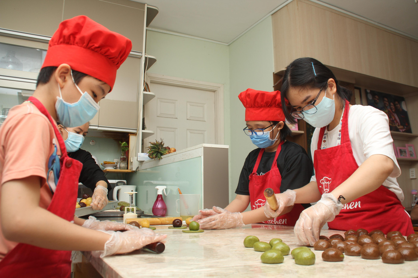 Mỗi người một tay để gửi lan tỏa tình thương đến những tình nguyện viên, y bác sỹ ở tuyến đầu, các bệnh nhi mắc COVID. Nguyên (áo hồng) và chị gái mình (áo trắng) hỗ trợ chị Dung chuẩn bị cho mẻ bánh trung thu.