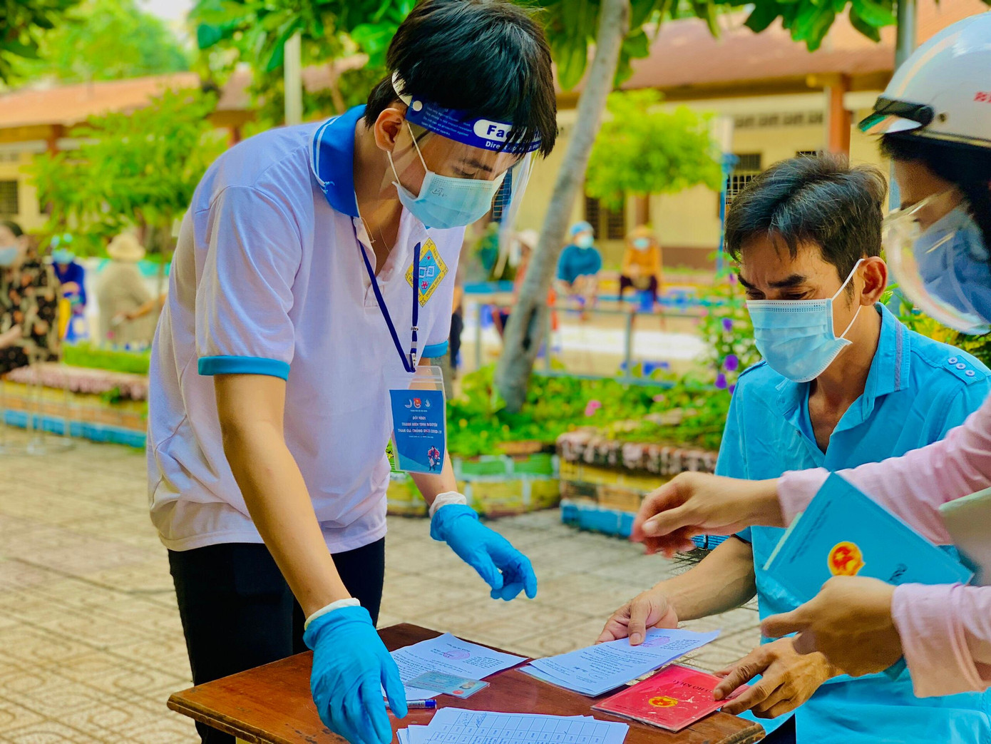 Nguyễn Thanh Tâm hướng dẫn bà con ghi tờ khai trước khi tiêm vắc xin.