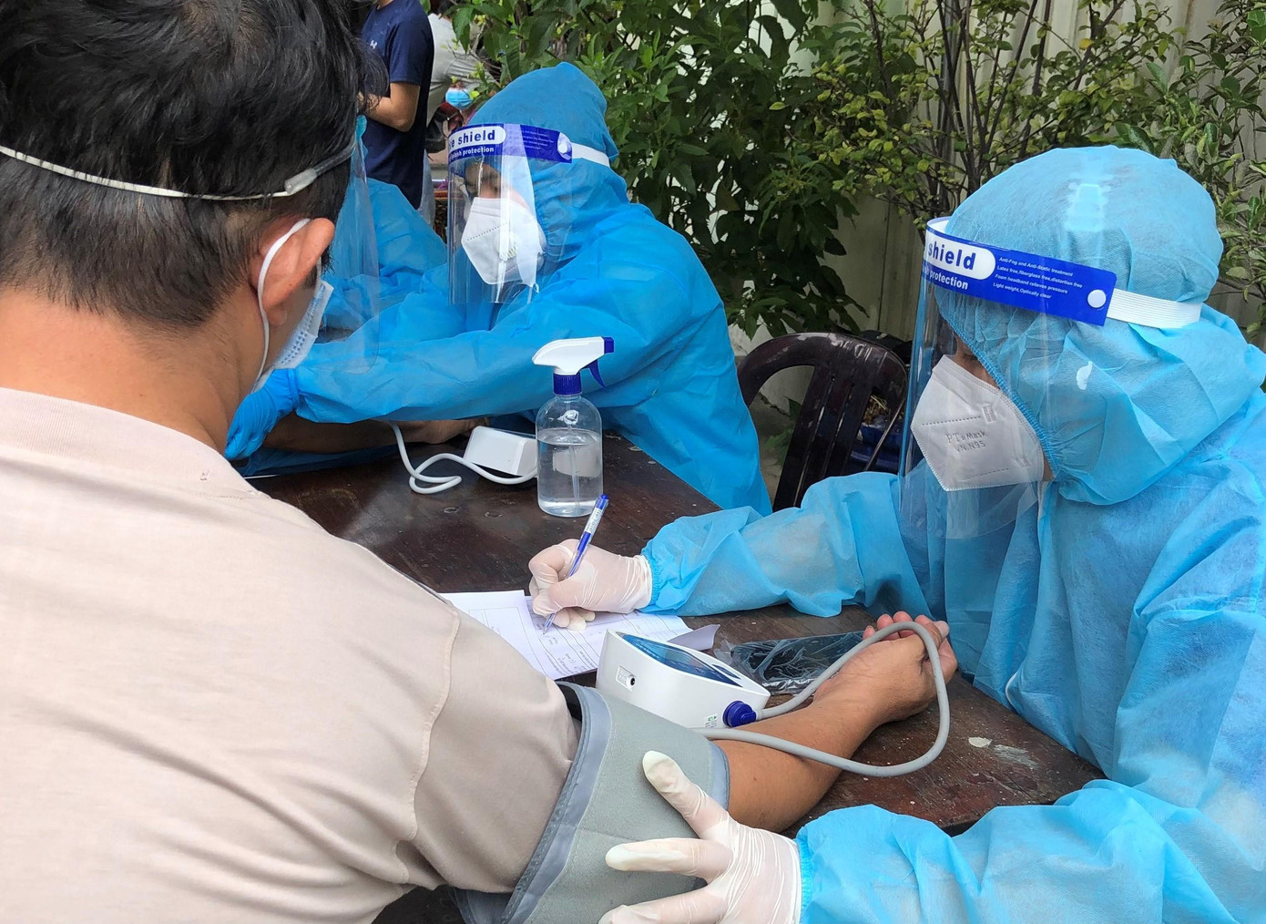 Thanh Tâm hỗ trợ đo huyết áp cho người dân trước khi tiêm vắc xin.