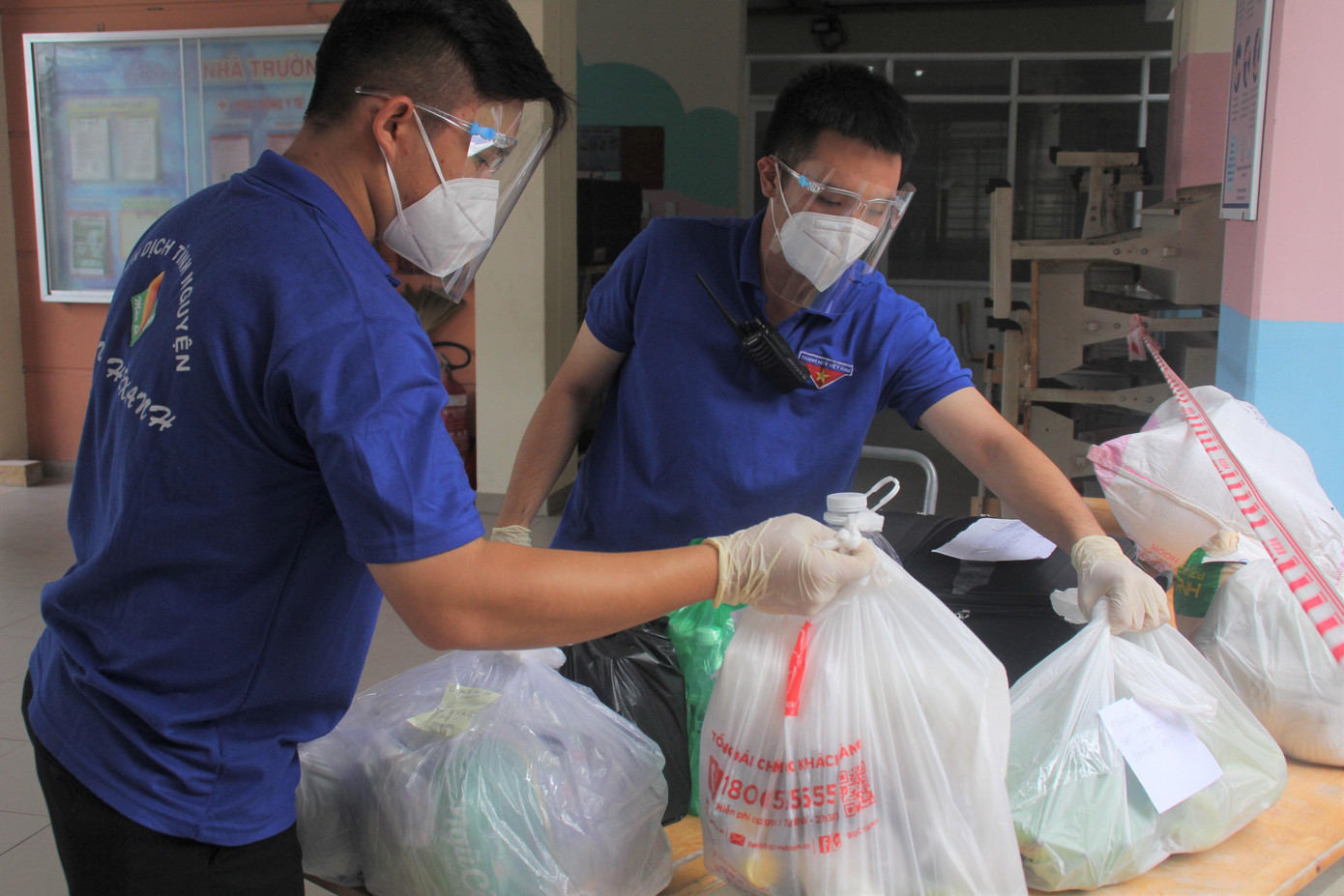 Đôi bạn có hình thể &quot;lực lưỡng&quot; nhất đội là Phạm Ngọc Hoàng (bên phải) và Nguyễn Thành Lợi vừa tiếp nhận hàng hóa từ bên ngoài và đưa vào khu cách ly. Tiếp đến, các bạn tình nguyện viên mặc bảo hộ kín kẽ mới được phép chuyển vào khu vực của bệnh nhân.