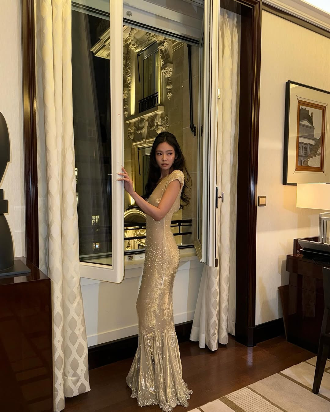 Là khách mời V.I.P, Jennie xuất hiện nổi bật với chiếc váy tông nude vàng lấp lánh. Váy thiết kế đuôi cá tôn triệt để đường cong tinh tế của nữ thần tượng. Phần ngực xẻ sâu táo bạo tăng thêm vẻ quyến rũ, khiêu khích. Trong khi đó, chất liệu vải bóng mềm kèm theo đính kết pha lê và ngọc trai giúp Jennie toát lên vẻ vương giả.