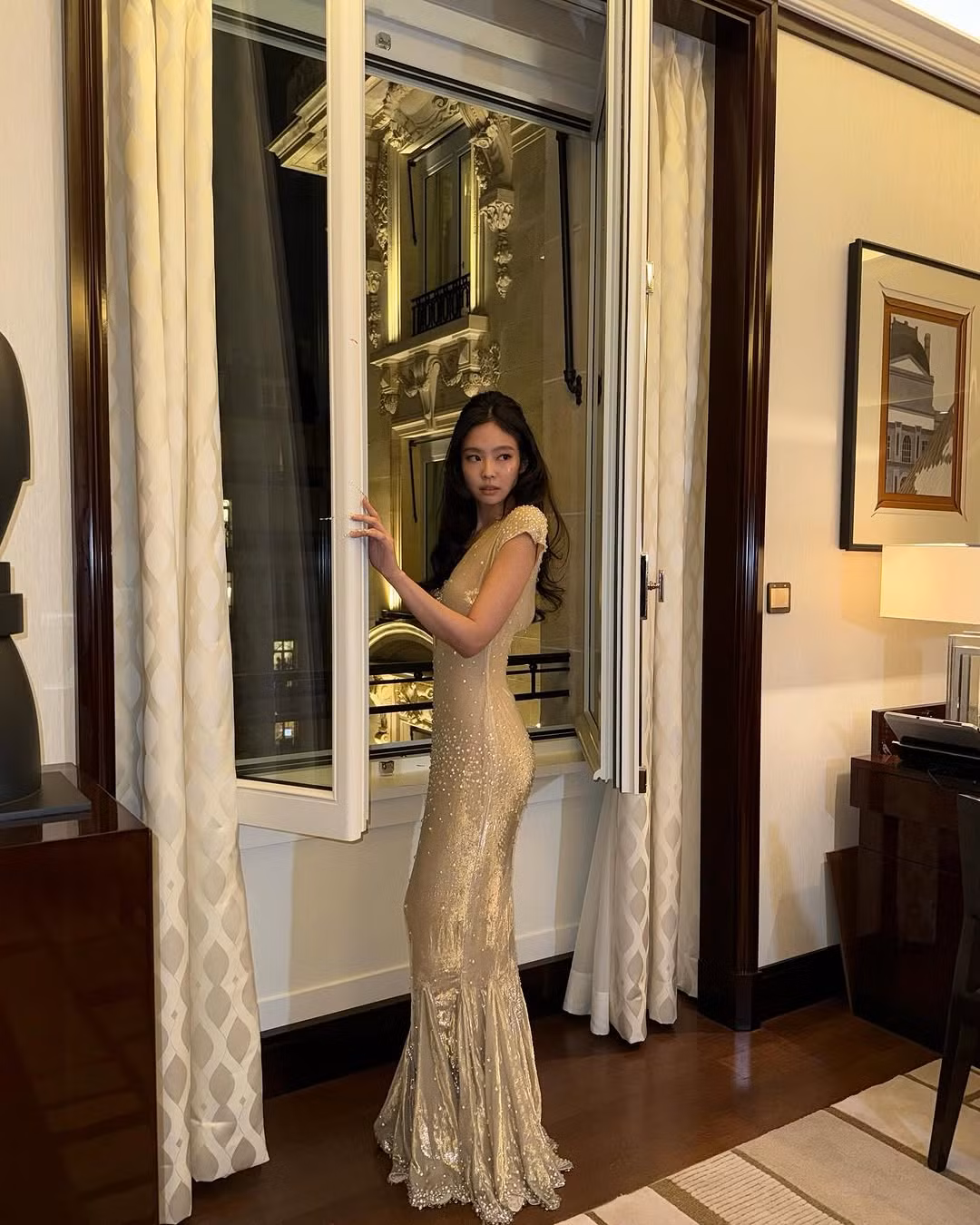 Là khách mời V.I.P, Jennie xuất hiện nổi bật với chiếc váy tông nude vàng lấp lánh. Váy thiết kế đuôi cá tôn triệt để đường cong tinh tế của nữ thần tượng. Phần ngực xẻ sâu táo bạo tăng thêm vẻ quyến rũ, khiêu khích. Trong khi đó, chất liệu vải bóng mềm kèm theo đính kết pha lê và ngọc trai giúp Jennie toát lên vẻ vương giả.