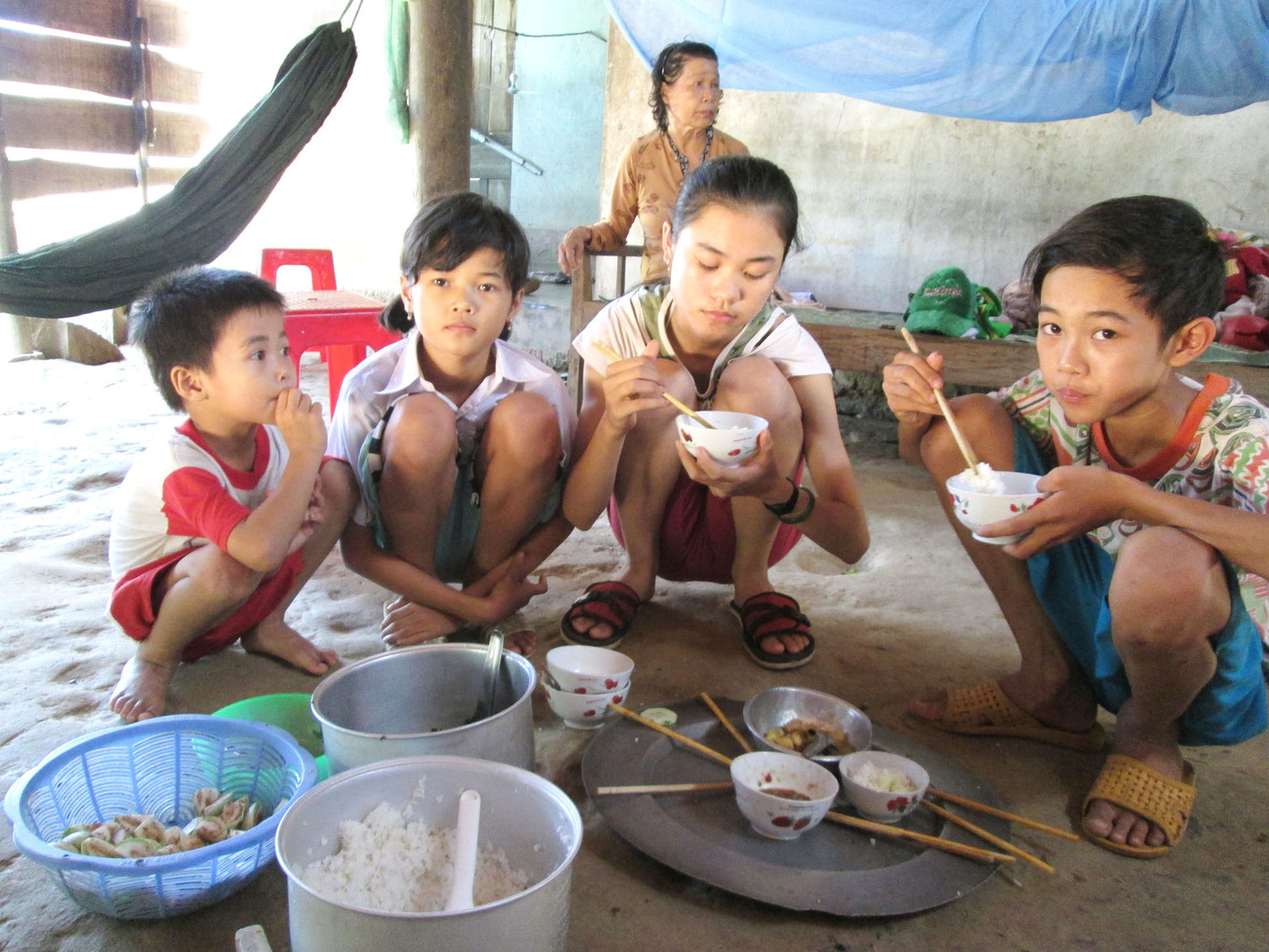 Bốn cháu bé mồ côi cha, giờ xúm xít bên mâm cơm nghèo thiếu mẹ. Ảnh: Thu Dịu