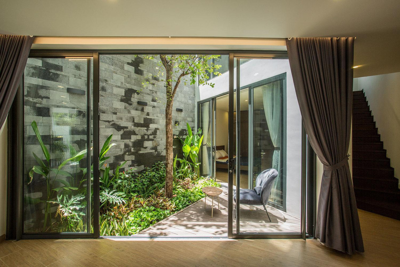 Tầng 1 là phòng ngủ của vợ chồng chủ nhà và đứa con nhỏ. Để đón được tối đa ánh sáng và không khí tự nhiên, cả hai phòng ngủ đều có cửa sổ kính lớn nhìn ra giếng trời để luôn có không khí trong lành trong các phòng ngủ.