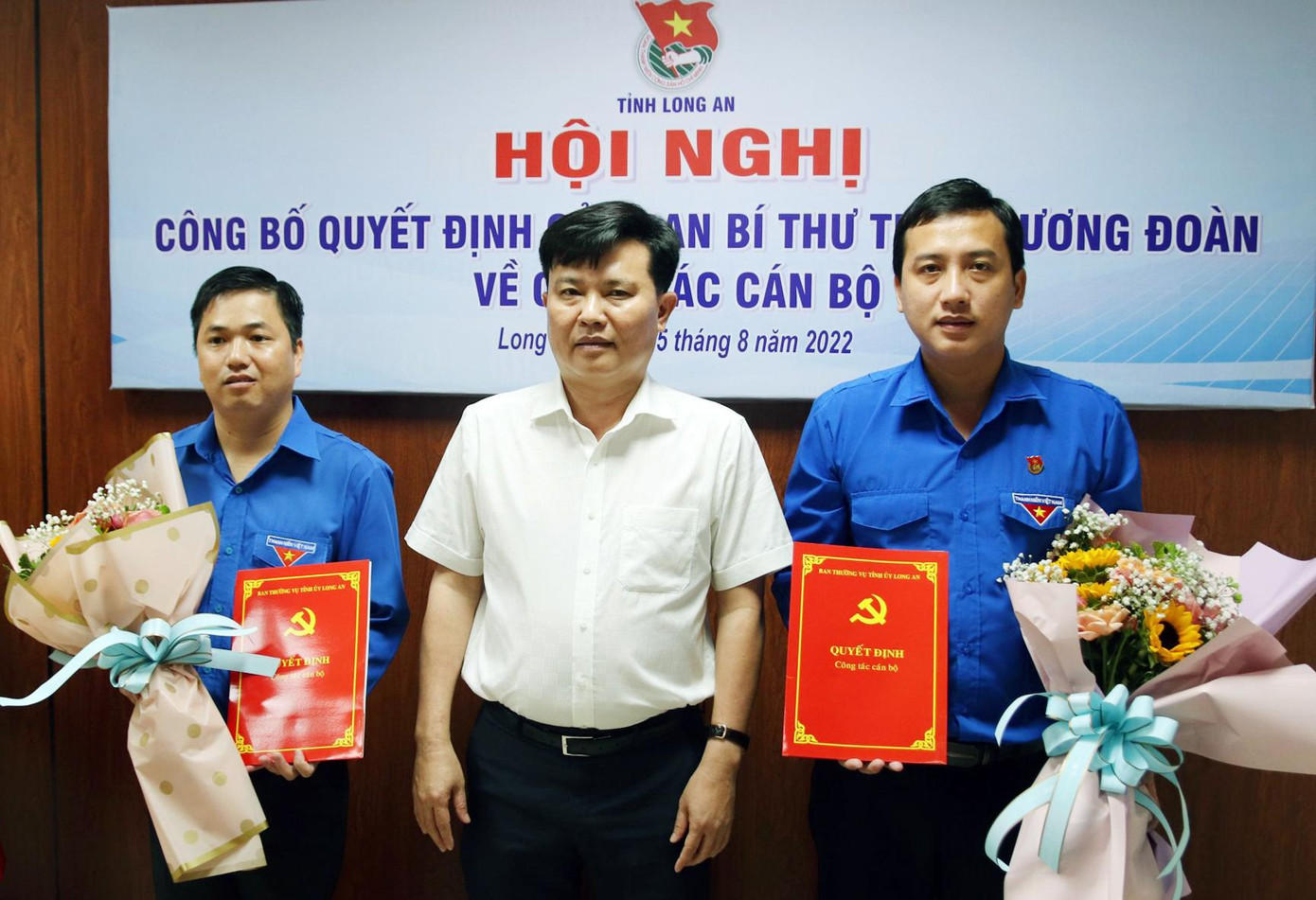Ông Nguyễn Thanh Hải trao quyết định, tặng hoa chúc mừng anh Trần Hải Phú (ngoài cùng bên phải) và anh Phạm Văn Hậu (ngoài cùng bên trái)