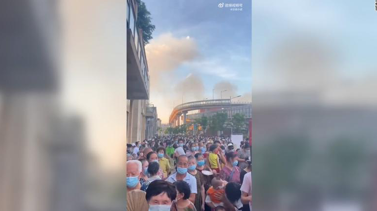 Bức ảnh người dân Trùng Khánh xếp hàng xét nghiệm COVID-19 trên nền trời có nhiều đám khói bốc lên từ cháy rừng