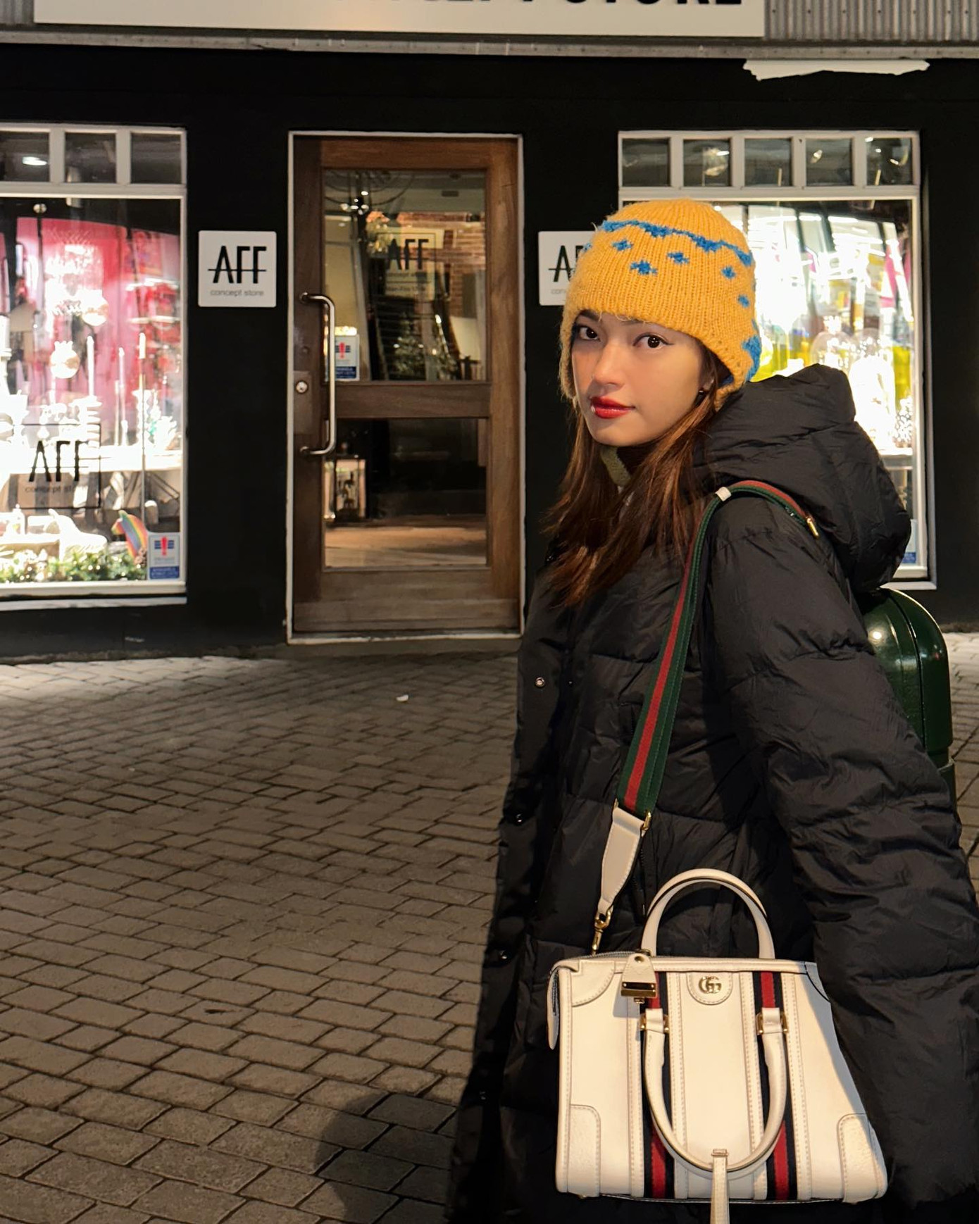 Kết hợp cùng chiếc áo phao dáng rộng dài, túi xách của Gucci, Châu Bùi đội mũ len phi công màu vàng với họa tiết đơn giản. Theo nhận xét của người hâm mộ, chiếc mũ này có vẻ theo phong cách &quot;thiếu nhi&quot;, thế nhưng với Châu Bùi, nó lại có tác dụng làm tôn lên gương mặt góc cạnh.