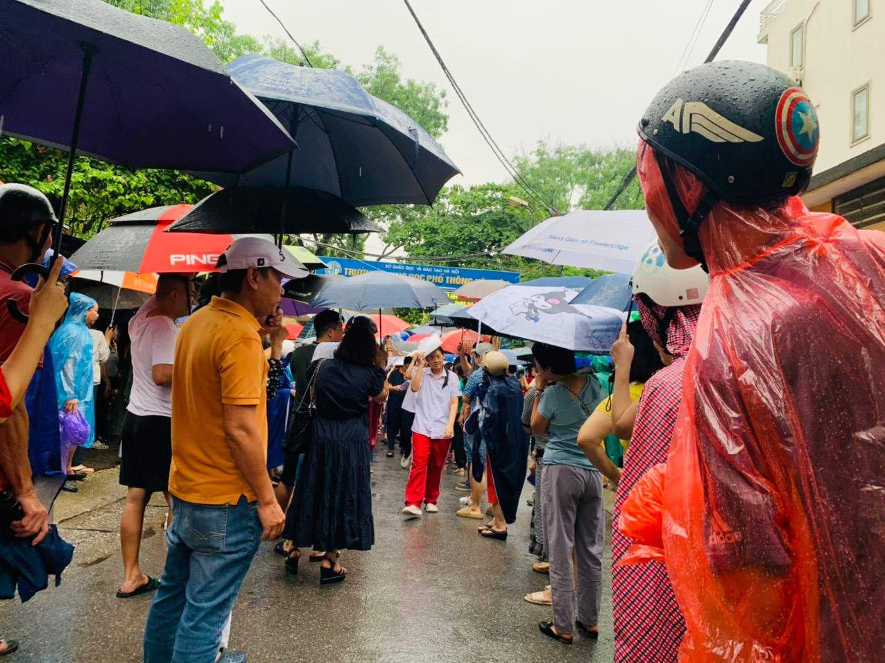 Bố mẹ ngóng trông con đi từ phòng thi ra và sẵn sàng ô và áo mưa đón con Bố mẹ ngóng trông con đi từ phòng thi ra và sẵn sàng ô và áo mưa đón con