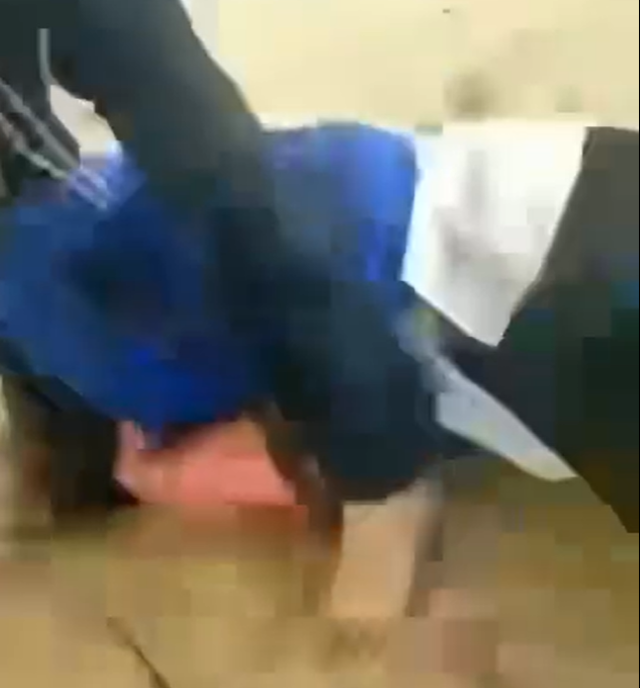 Nữ sinh nằm dưới đất bị đối tượng dùng chân đạp vào vùng bụng Ảnh cắt từ clip