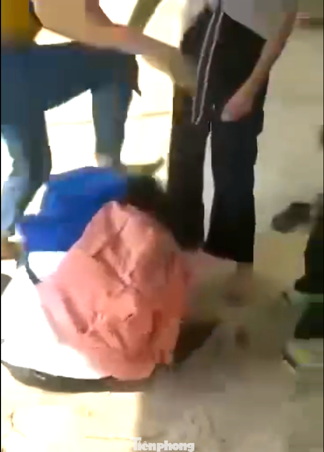 Nữ sinh ngồi dưới đất bị nhóm nữ dùng chân đạp vào đầu. Ảnh: Cắt từ clip.