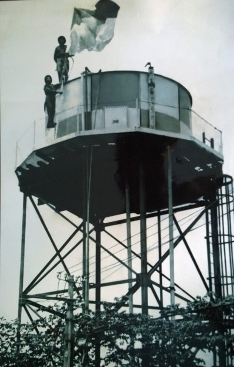 Chiến sĩ Phạm Văn Lãi và Nguyễn Văn Cẩn cắm cờ giải phóng trên đỉnh tháp nước tại Trại Davis lúc 9h30 phút ngày 30/4/1975 (Ảnh: T.L)