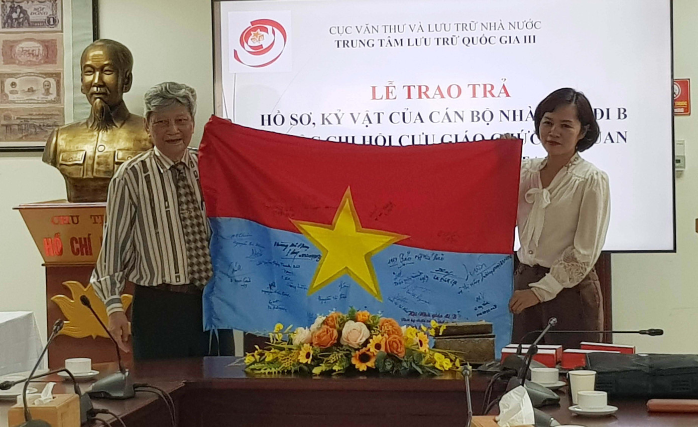Ông Đỗ Trọng Văn, Chi hội trưởng Chi hội Cựu giáo chức đi B của Bộ Giáo dục và Đào tạo trao lá cờ có chữ ký của các hội viên Chi hội gửi tặng Trung tâm Lưu trữ Quốc gia III. Ảnh: Kiến Nghĩa.