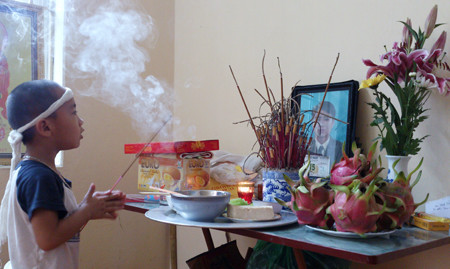 Cháu Đức Anh thắp hương cho bố. Ảnh: Đại Huệ