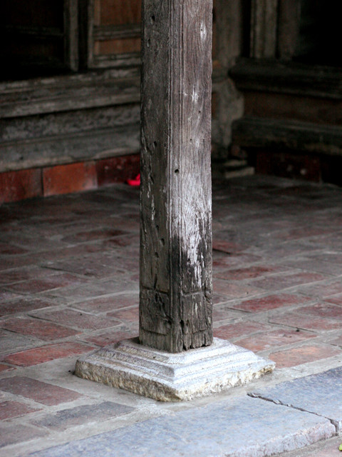 Cột gỗ, được kê bằng đá chống cho khung nhà