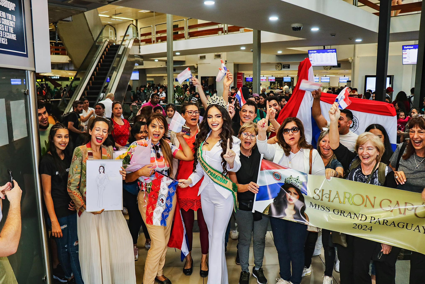 Sharon Capo, đại diện của Paraguay cũng đã sang Campuchia để tham dự cuộc thi năm nay. Người đẹp diện bộ trang phục màu trắng thanh lịch ở sân bay, được đông đảo người thân và khán giả tới ủng hộ.