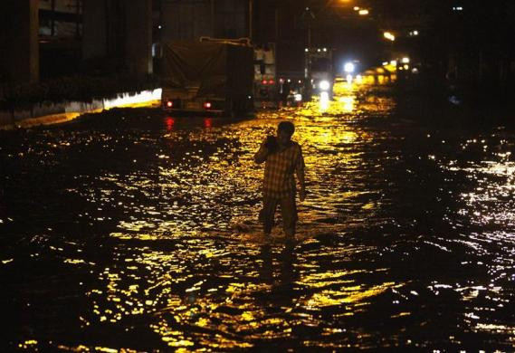 Một người dân lội trong dòng nước lũ trên đường phố ở quận Don Muang (Bangkok)