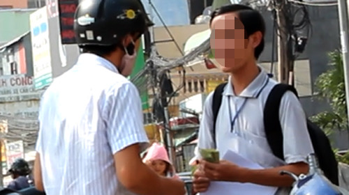 T. (phải) trao giấy xác nhận kinh nghiệm liên thông cho một người và nhận 300.000 đồng