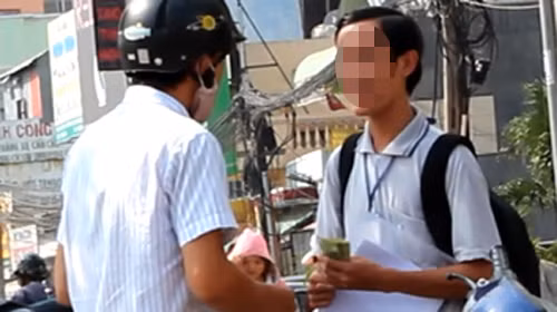 T. (phải) trao giấy xác nhận kinh nghiệm liên thông cho một người và nhận 300.000 đồng