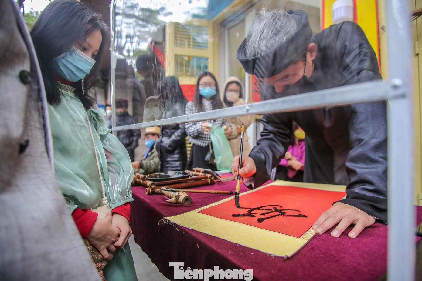 Ông đồ cho chữ qua tấm chắn trong những ngày đầu năm. Ông đồ cho chữ qua tấm chắn trong những ngày đầu năm.