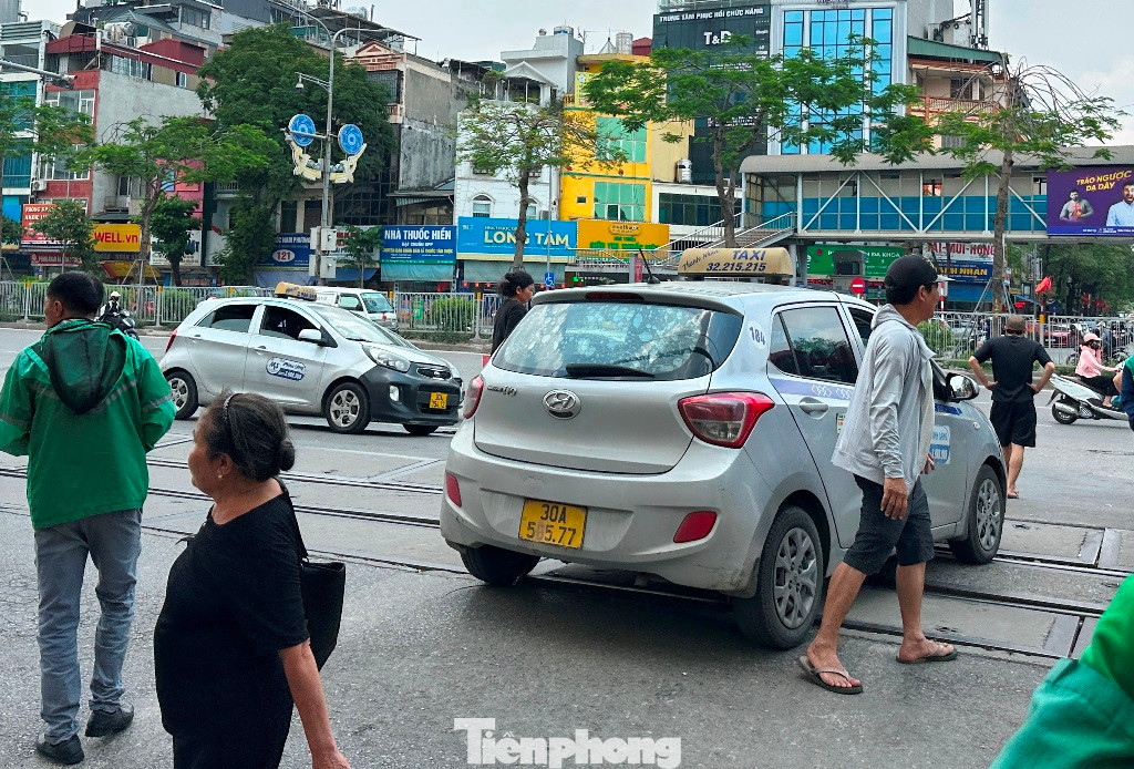 Ở cổng ra, một xe taxi có biển 30A-56577 (có số 6 bị mờ) đã đứng giữa cổng ra và tài xế xuống đường chào mời khách.