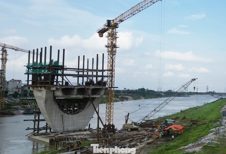 Trao đổi với PV Tiền Phong, ông Trần Anh Tuấn, Cty Cổ phần Tập đoàn Đạt Phương (nhà thầu chính) thi công dự án cho biết, do dầm cầu thi công bằng công nghệ đúng hẫng nên để đi công ở được phần dầm vượt sông, cần phải làm xong phần dầm cầu cạn ở hai bên bờ để tạo đối xứng. Tuy nhiên, do phần mặt bằng ở cả quận Long Biên và Gia Lâm chưa có nên hiện các trụ cầu được xây dựng ở lòng sông đang đứng chơ vơ, không thể thi công phần đúc dầm.