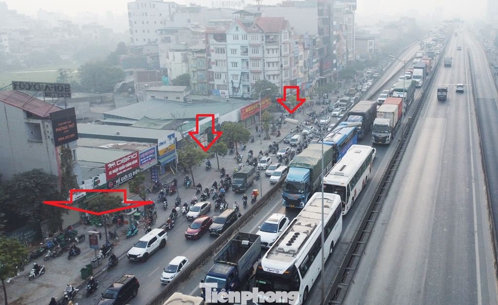 Ùn tắc kéo dài khiến nhiều người đi xe máy đã phớt lờ cả quy định xử phạt cao cho xe lách lên vỉa hè (mũi tên đỏ) để di chuyển cho kịp giờ làm, giờ học.