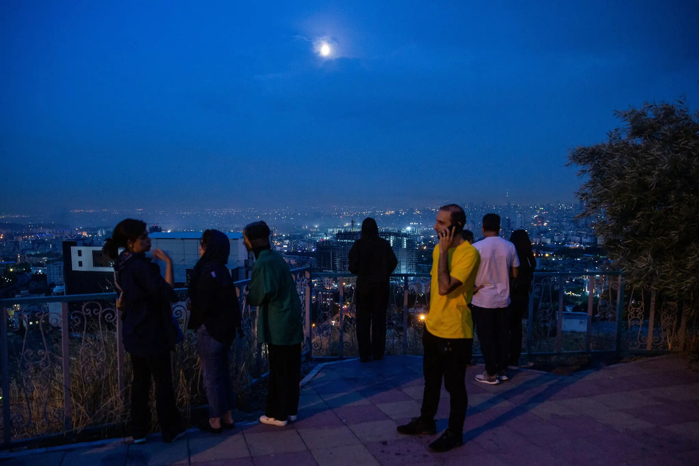 Người dân Iran tập trung trên một ngọn đồi để quan sát khói bốc lên sau vụ không kích của Israel vào Tehran rạng sáng 13/6/2025. Ảnh: New York Times. Người dân Iran tập trung trên một ngọn đồi để quan sát khói bốc lên sau vụ không kích của Israel vào Tehran rạng sáng 13/6/2025. Ảnh: New York Times.
