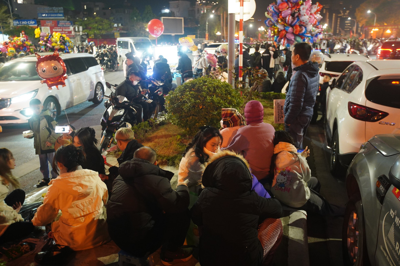 Người dân ngồi trên dải phân cách đường Nguyễn Hoàng Tôn chờ xem màn pháo hoa đặc sắc đón chào năm mới.