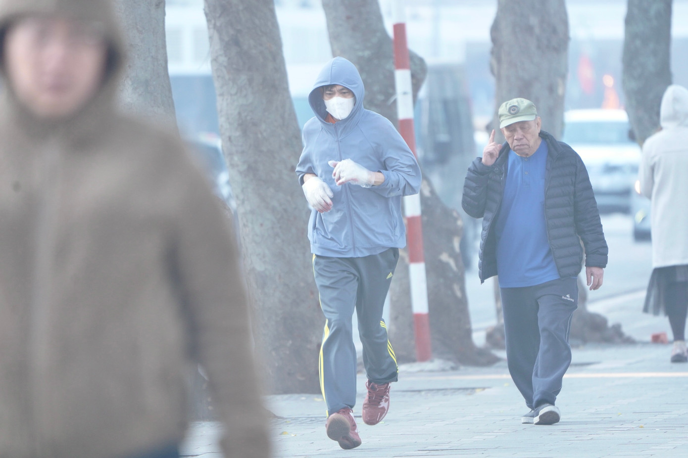 Người dân tập thể dục quanh hồ Hoàn Kiếm sáng sớm với trang phục chống lạnh.