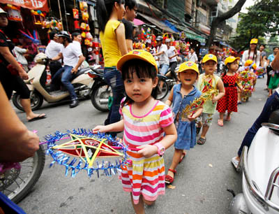 Các em nhỏ được người lớn cho đi chơi trên phố với đèn ông sao. Các em nhỏ được người lớn cho đi chơi trên phố với đèn ông sao