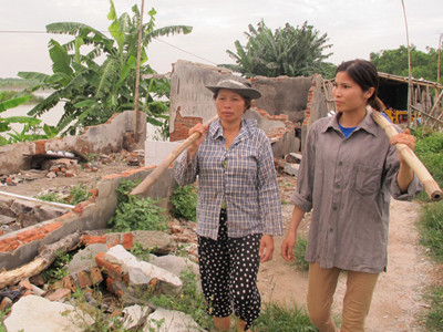 Bà Nguyễn Thị Thương (trái, vợ ông Vươn) và bà Phạm Thị Hiền (vợ ông Quý) dọn dẹp ngôi nhà bị phá hủy và tiếp tục cuộc sống trong ngôi nhà tạm tại khu đầm. Ảnh: T.Hoàng