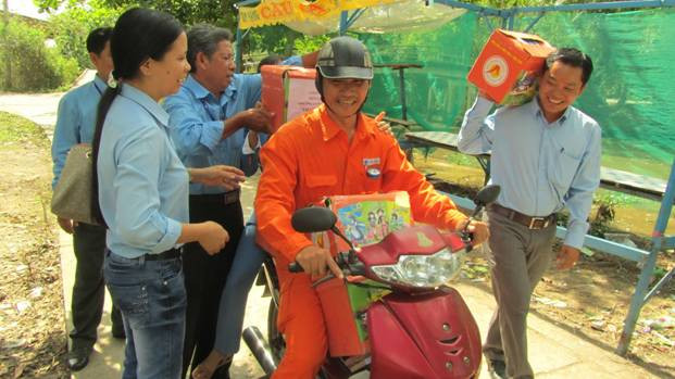 Nhân viên Công ty Điện lực Kiên Giang vận chuyển quả và tờ rơi tuyên truyền tiết kiệm điện đến các vùng sâu