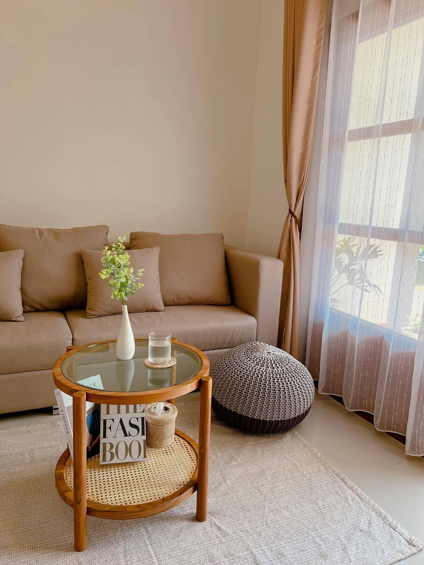 Không gian phòng khách thoáng đãng nhờ có cửa lớn hướng ra vườn đón gió mát và ánh sáng. Bên cạnh yếu tố truyền thống, KTS còn bố trí đan xen những chất liệu thô mộc như bàn trà bằng gỗ kết hợp chất liệu mây, thảm trải sàn dệt bằng sợi đay, rèm cửa 2 lớp bằng vải thô và vải voan,… Nhờ đó mà không gian trong nhà vẫn bắt kịp xu hướng hiện đại.