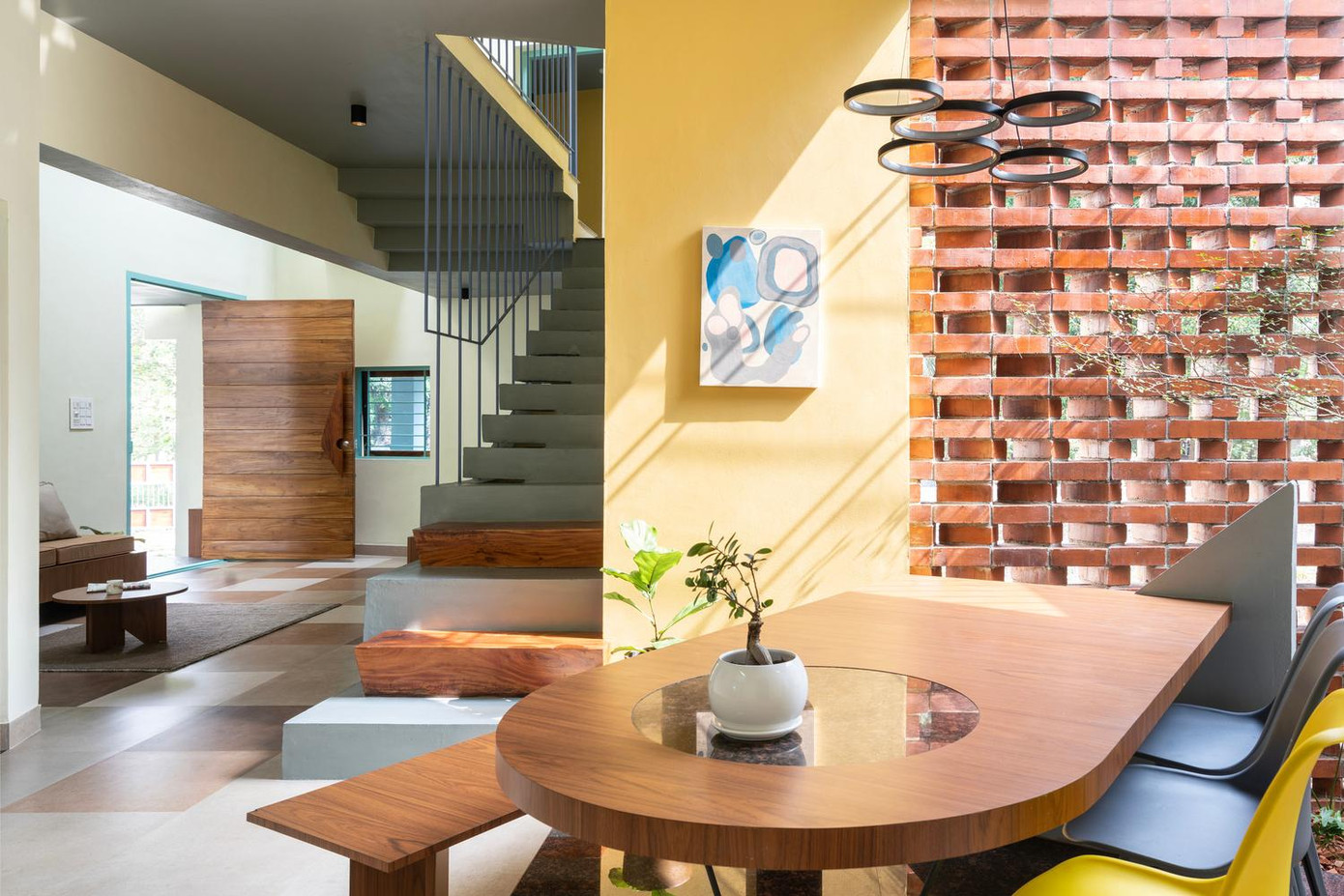 Không gian phòng khách, bếp và phòng ăn liên thông với nhau ở tầng 1, đồ nội thất chủ yếu bằng gỗ để tăng thêm sự ấm áp cho ngôi nhà. Tại khu vực phòng ăn, một bức tường ô thoáng được thiết kế để giúp không khí luôn mát mẻ.