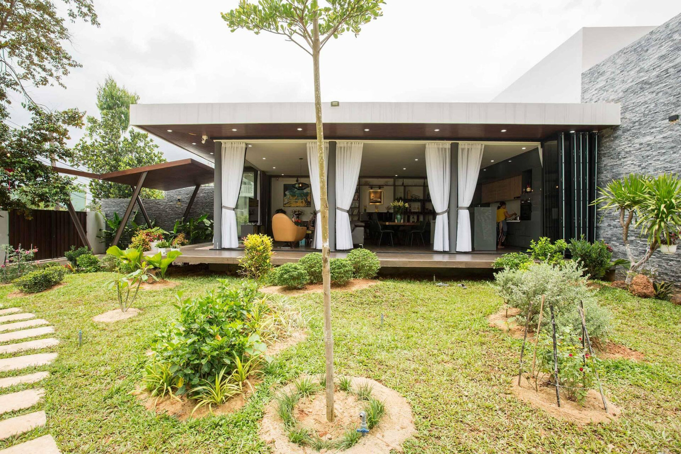 KTS còn tạo lối đi thông suốt từ nhà ra vườn. Các tấm bê tông to dần theo kiểu bậc thang để các thành viên thư giãn, trải nghiệm và tận hưởng cuộc sống trong lành, bình yên.