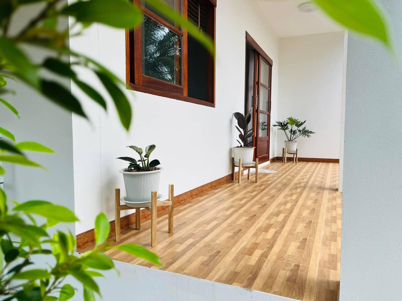 Ngôi nhà mang tông màu trắng chủ đạo, nổi bật giữa màu xanh của cây trái, tạo cảm giác thoáng đãng, mát mẻ và gần gũi với thiên nhiên. Kiến trúc sư (KTS) sử dụng cửa gỗ màu cánh gián truyền thống thay cho cửa kính để tạo sự đặc trưng cho ngôi nhà.