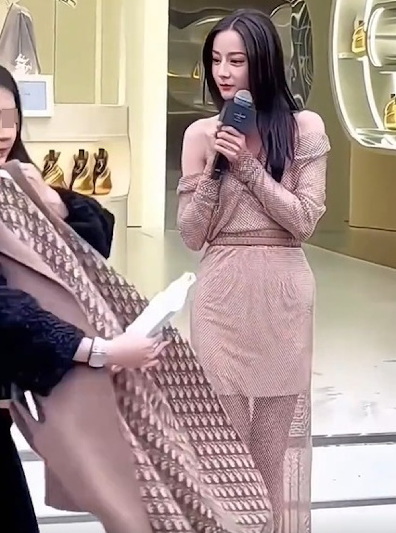 Địch Lệ Nhiệt Ba co ro vì bị lấy mất áo khoác giữa thời tiết giá lạnh.