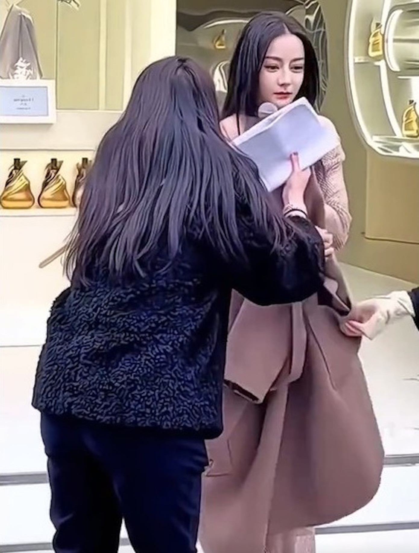 Địch Lệ Nhiệt Ba co ro vì bị lấy mất áo khoác giữa thời tiết giá lạnh.