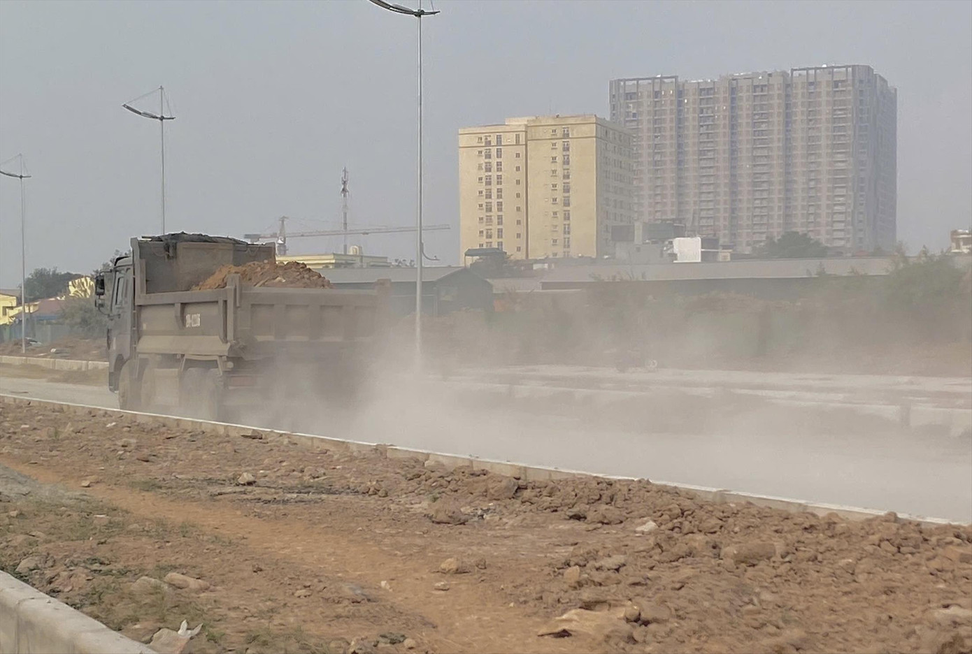 Bụi phát sinh khi xe tải ra, vào tại công trường trên đường Tây Tựu (gần đoạn giao với QL32), Bắc Từ Liêm, Hà Nội