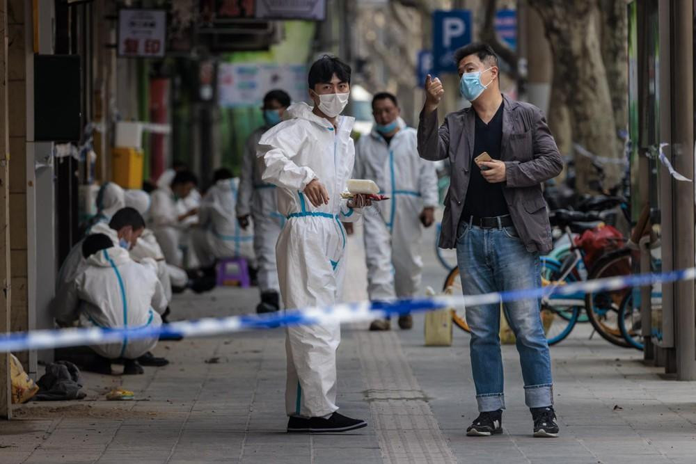 Nhân viên y tế mặc đồ bảo hộ đứng bên ngoài một toà nhà bị phong toả ở Thượng Hải ngày 14/3 Ảnh: EPA-EFE Nhân viên y tế mặc đồ bảo hộ đứng bên ngoài một toà nhà bị phong toả ở Thượng Hải ngày 14/3 Ảnh: EPA-EFE