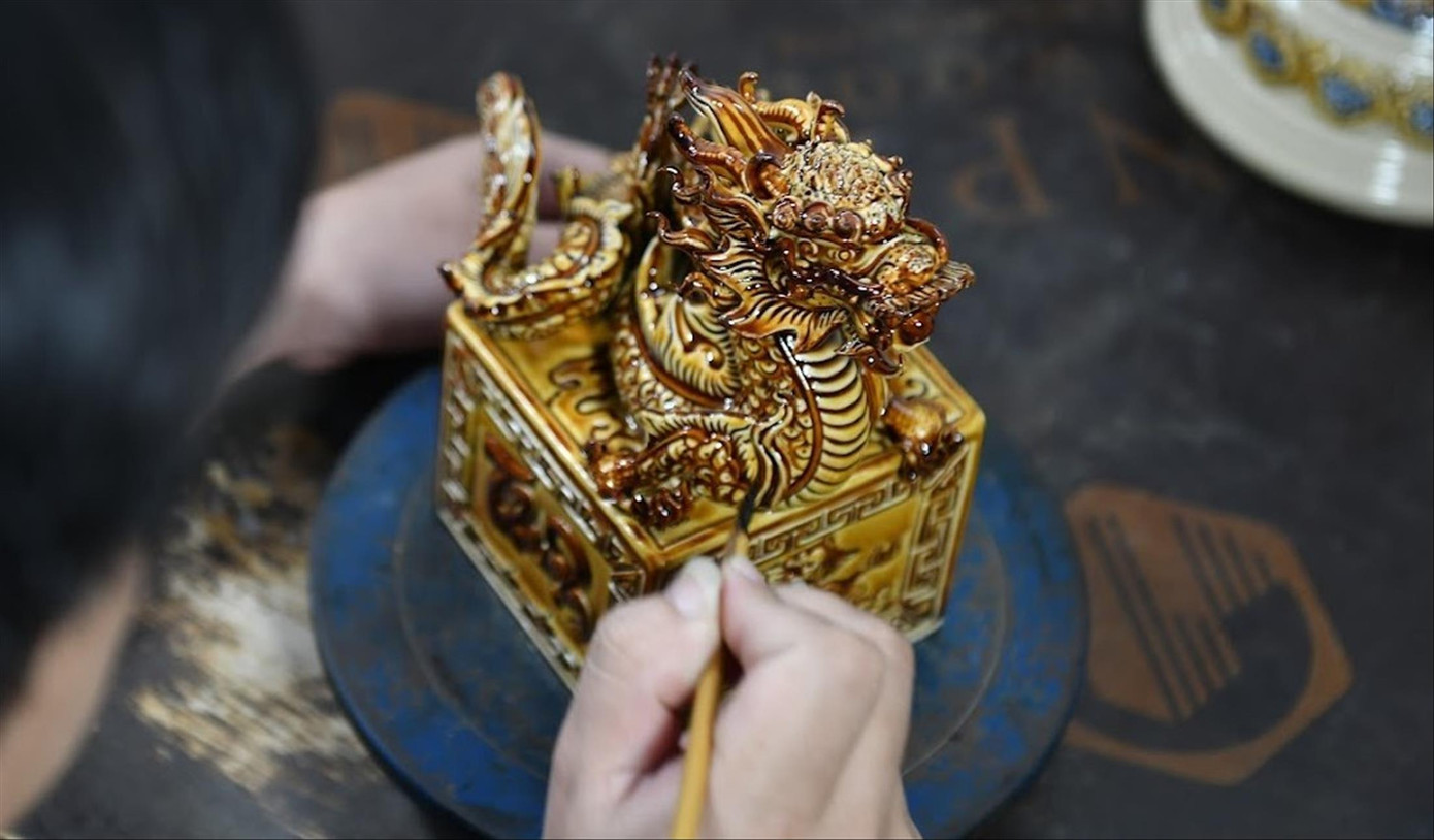 Nghệ nhân Bát Tràng tạo đường nét lên chiếc ấn rồng bằng gốm. Nghệ nhân Bát Tràng tạo đường nét lên chiếc ấn rồng bằng gốm.