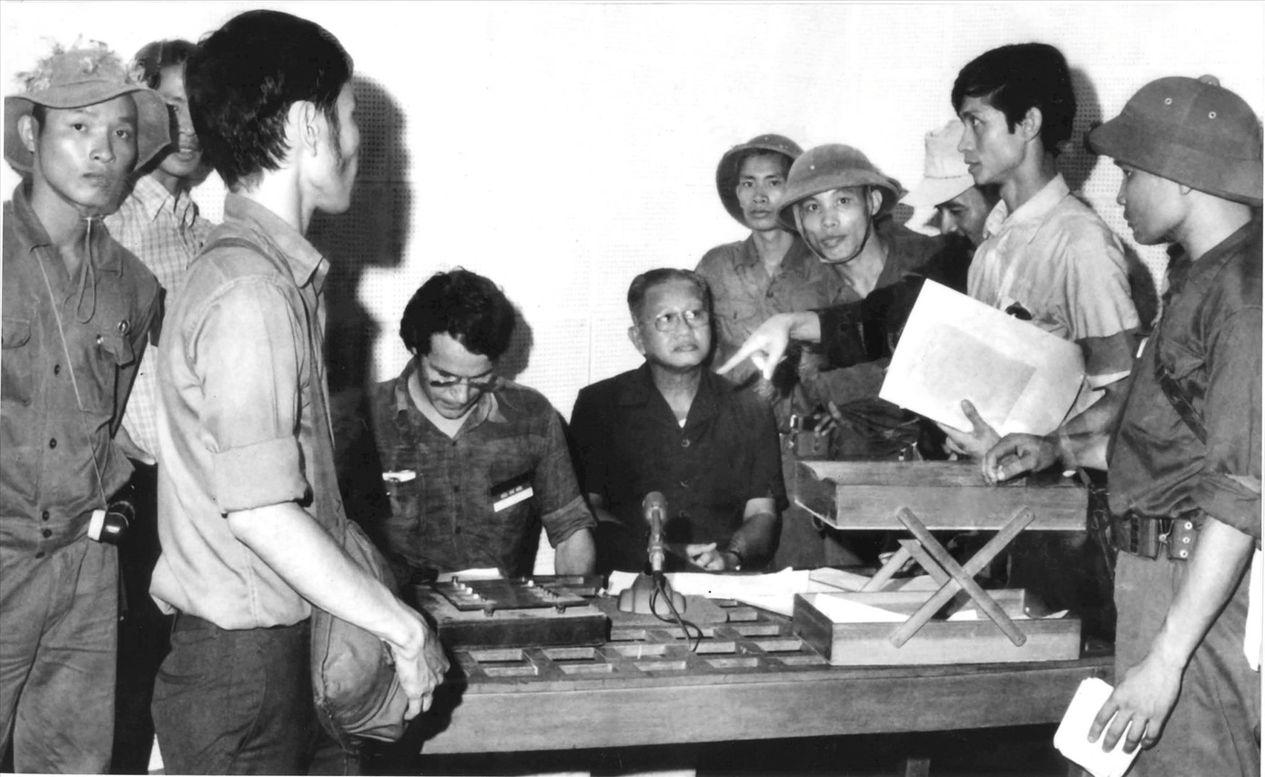 Tướng Dương Văn Minh tuyên bố đầu hàng tại Đài Phát thanh Sài Gòn trưa ngày 30/4/1975, KTS Nguyễn Hữu Thái cầm tập giấy màu trắng, đứng bên phải. Bức ảnh do nhà báo Kỳ Nhân, phóng viên ảnh hãng thông tấn AP Mỹ chụp.