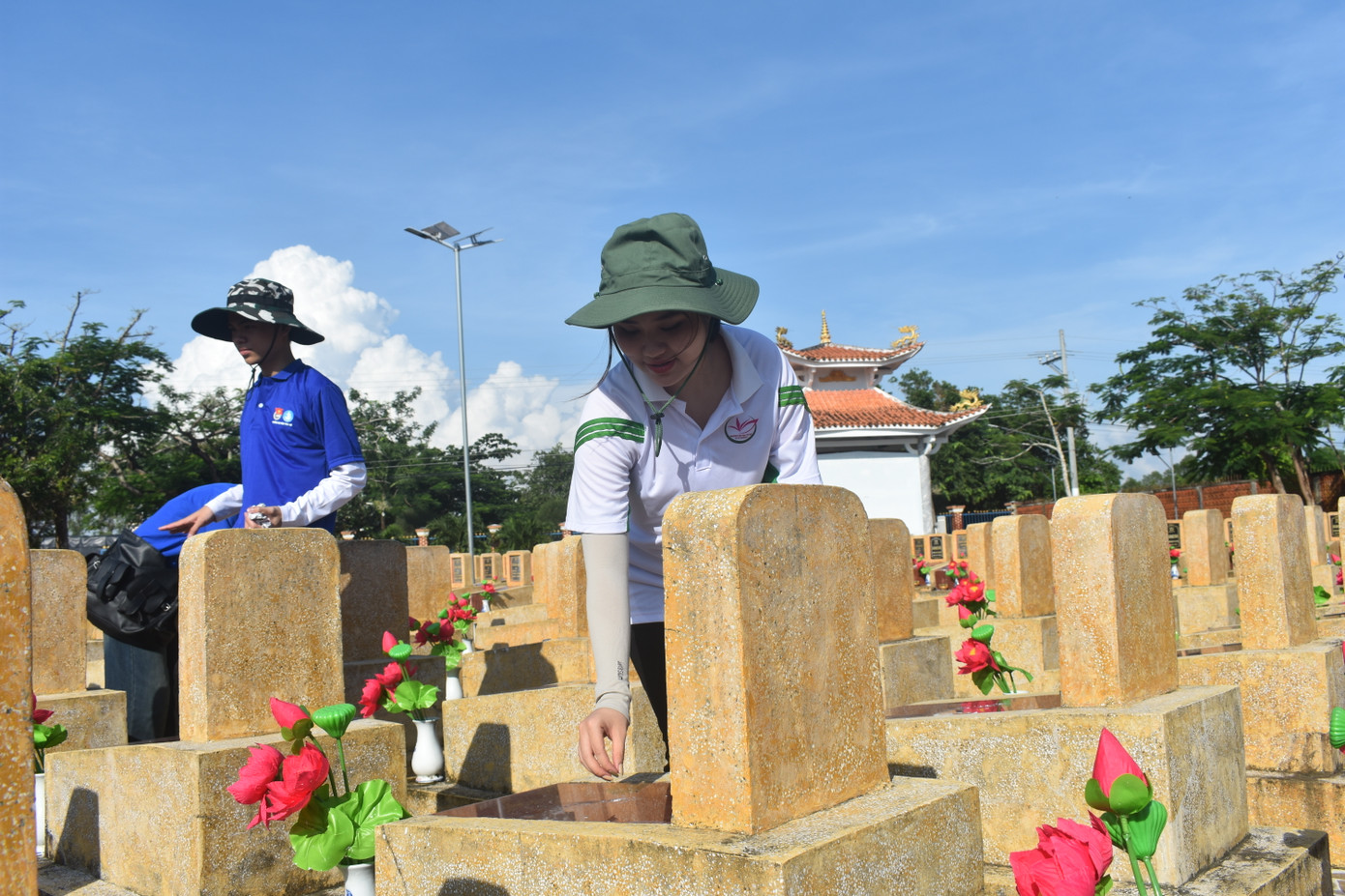 Các tình nguyện viên quét dọn nhà bia, phần mộ tại Nghĩa trang xã Nguyễn Phích (huyện U Minh)