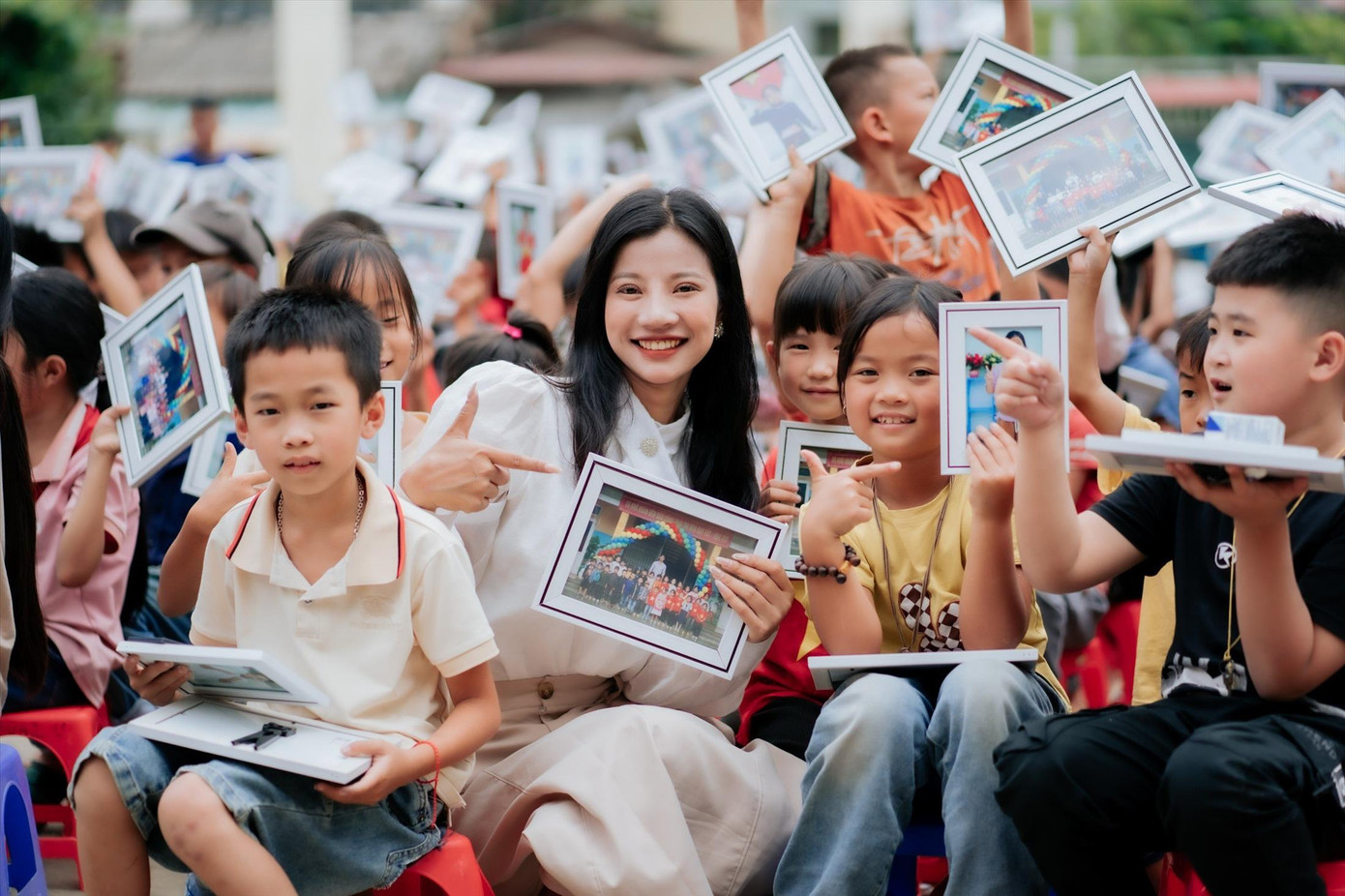 Các em nhỏ xã Du Già khoe ảnh kỷ yếu cùng các thành viên dự án Kỷ yếu trên bản