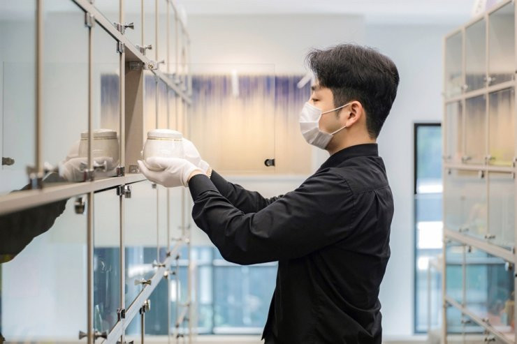 Người trợ giúp tang lễ thú cưng trân trọng cầm chiếc bình chứa hài cốt hỏa táng của thú cưng đã qua đời tại lò hỏa táng Ảnh: The Korea Times