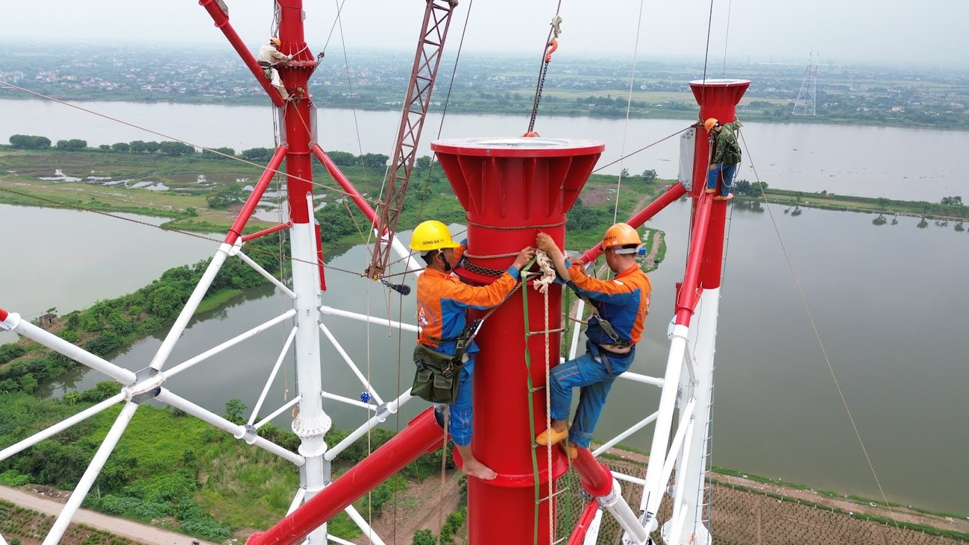 Công nhân thi công trên cột bắc qua sông Hồng. Ảnh: Hoàng Mạnh Thắng. Công nhân thi công trên cột bắc qua sông Hồng. Ảnh: Hoàng Mạnh Thắng.