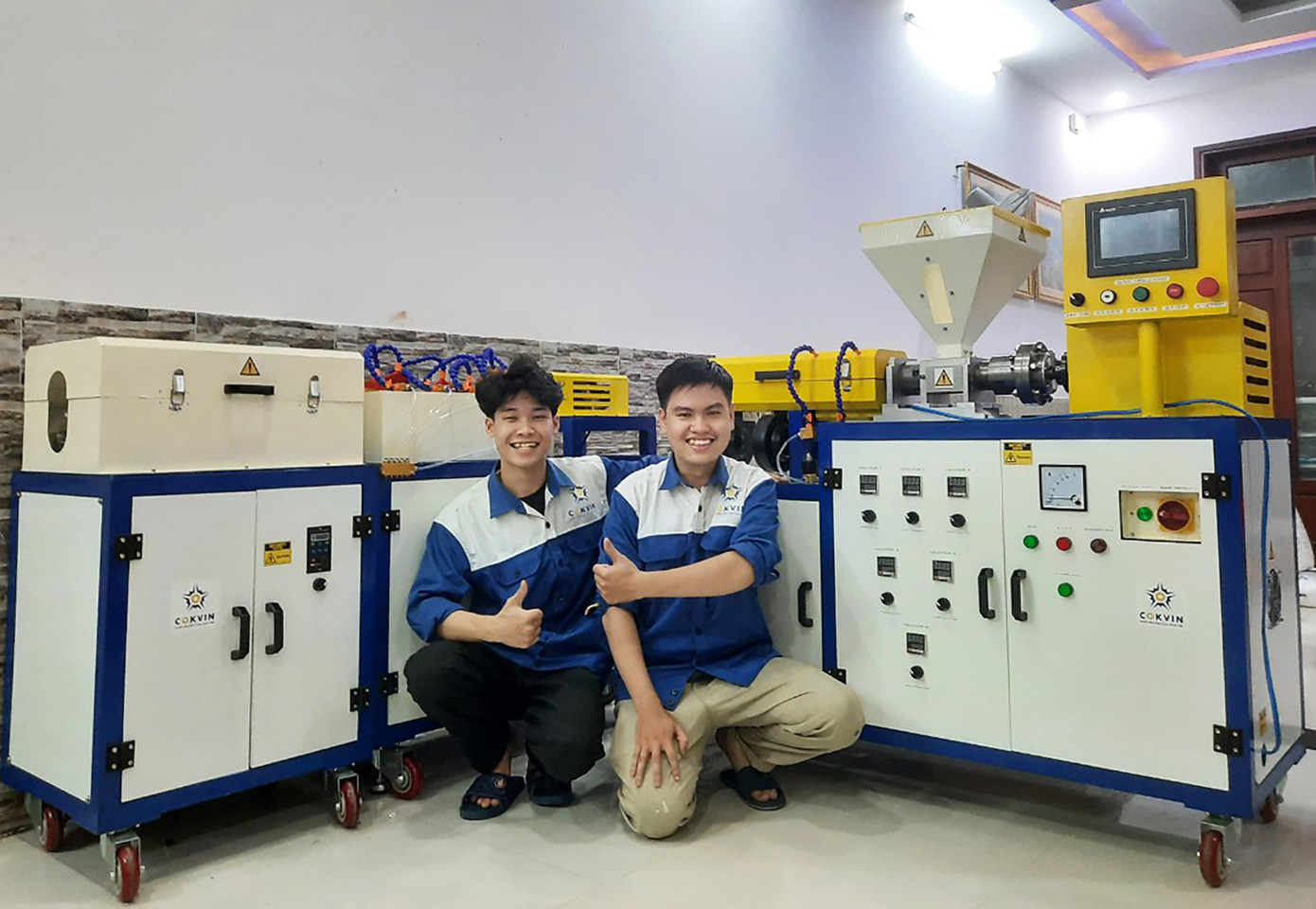 Hai bạn Phan Lê Kỷ Nguyên và Hoàng Tuấn Hiệp (khoa Cơ khí, trường ĐH Bách khoa - ĐH Đà Nẵng) bên “Máy sản xuất ống xoắn nhựa PE bọc dây điện” vừa hoàn thành