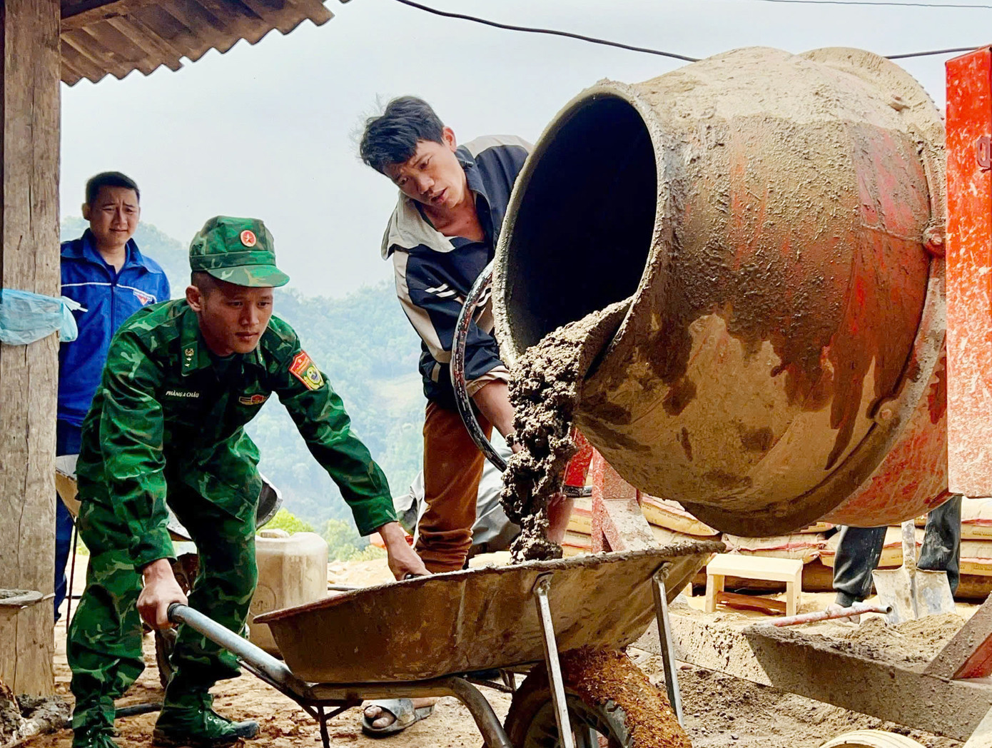 Cán bộ, chiến sĩ bộ đội biên phòng giúp dân chuyển vật liệu xây dựng nhà mới.