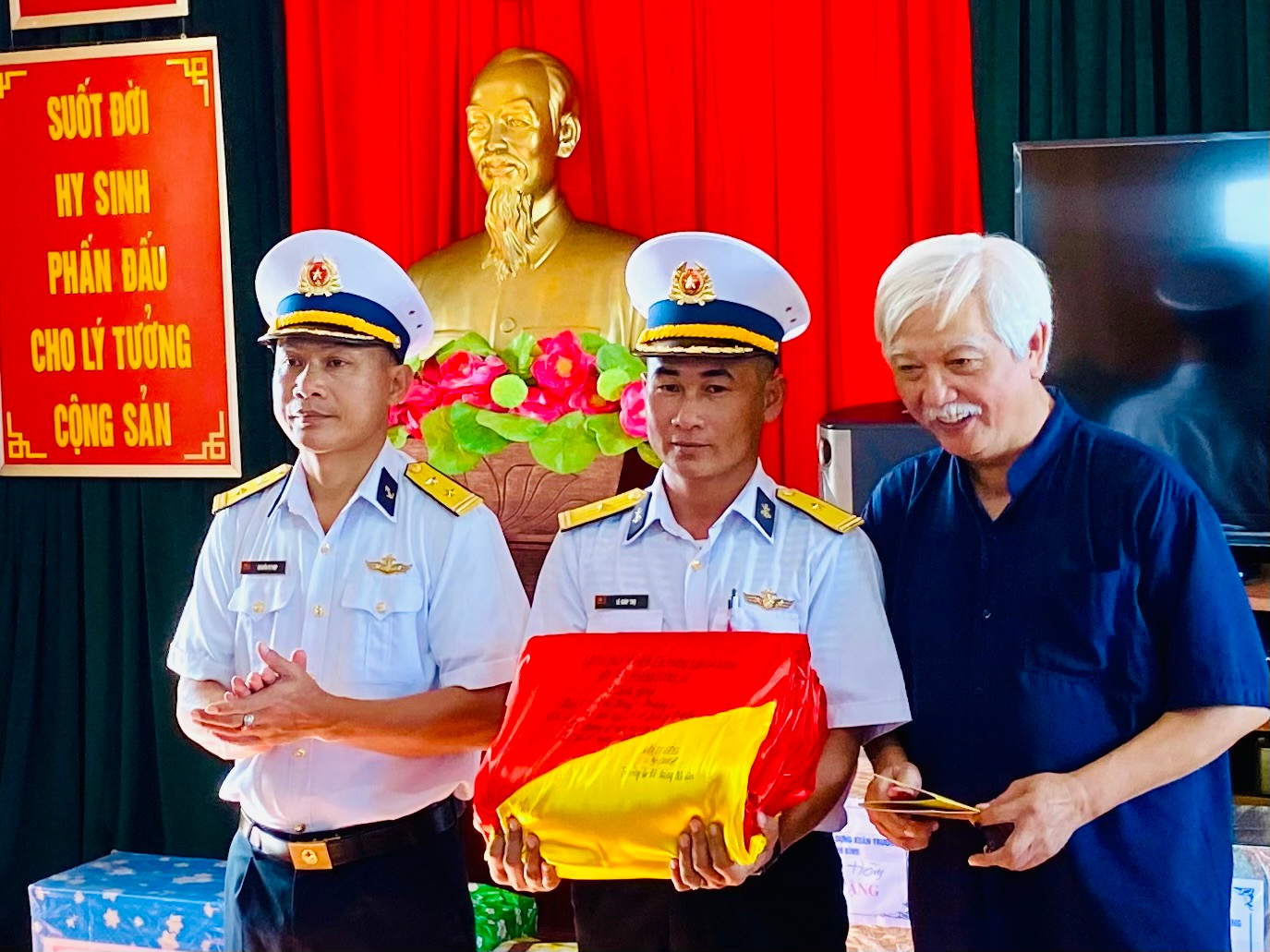 Nhà sử học Dương Trung Quốc trao lá cờ của Đồn Biên phòng Lũng Cú gửi tặng đảo Sinh Tồn Đông cho chỉ huy trưởng và chính trị viên đảo. Ảnh: Lê Xuân Sơn